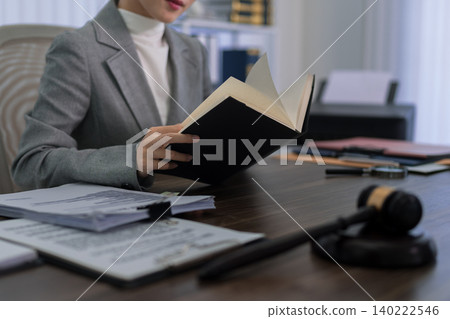 professional Asian lawyer reading legal document book studying law case research at office desk with gavel paperwork preparing trial courtroom legal professional Asian lawyer reading legal document book studying law case research at office desk with gavel paperwork preparing trial courtroom legal 140222546