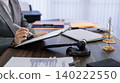 professional lawyer writing legal document at desk with gavel and justice scales in law office preparing court case consultation business meeting 140222550