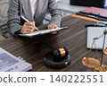 lawyer signing digital tablet with stylus at desk with gavel in office for legal document review contract law professional legal services attorney workplace 140222551