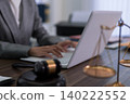 professional lawyer attorney working on laptop computer with gavel scale justice at office desk legal consultant researching case law preparing court document 140222552