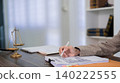 lawyer attorney reviewing contract document at desk in modern law office with justice scale symbol reviewing legal paperwork for client consultation 140222555