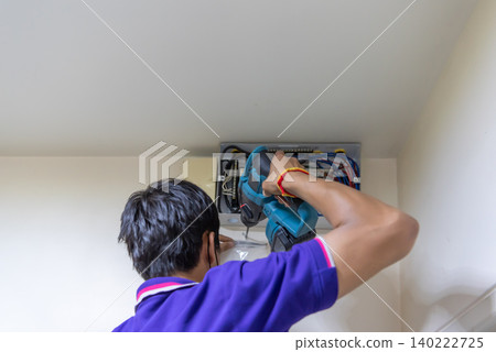 Technician using power drill while installing servicing an electrical distribution panel Indoor electrical maintenance work wiring professional tools 140222725