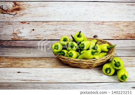 Fresh raw green bell pepper in bamboo basket on wooden background Fresh raw green bell pepper in bamboo basket on wooden background 140223251