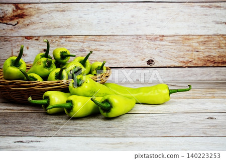 Fresh raw green bell pepper in bamboo basket on wooden background Fresh raw green bell pepper in bamboo basket on wooden background 140223253