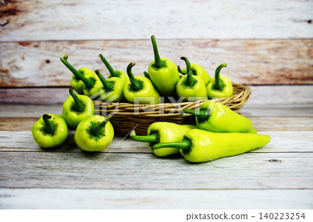 Fresh raw green bell pepper in bamboo basket on wooden background Fresh raw green bell pepper in bamboo basket on wooden background 140223254