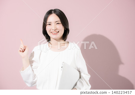 A cute, smiling female employee with a laptop against a pink background, presenting a business image of her pointing and recommending something. A cute, smiling female employee with a laptop against a pink background, presenting a business image of her pointing and recommending something. 140223457