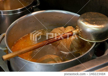 A close-up of the special soup made by simmering dashi packets in a large pot at a ramen shop. 140223484