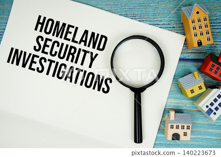 Notepad with "HIS Homeland Security Investigations" with magnifying glass and house model on wooden background 140223673