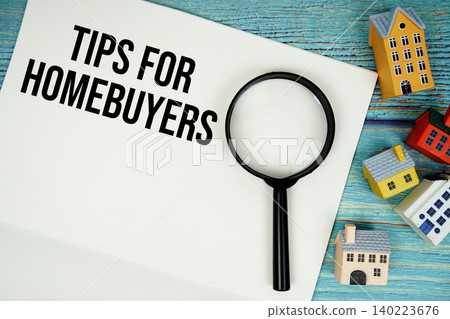 Notepad with "Tips For Homebuyers" with magnifying glass and house model on wooden background Notepad with "Tips For Homebuyers" with magnifying glass and house model on wooden background 140223676