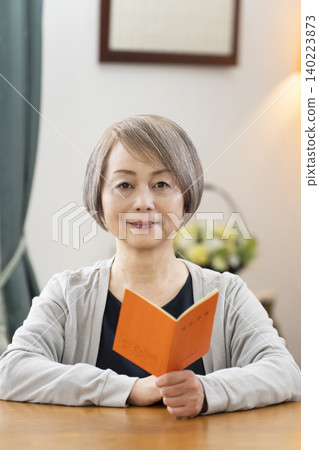 A senior woman looking at her pension book in the living room A senior woman looking at her pension book in the living room 140223873
