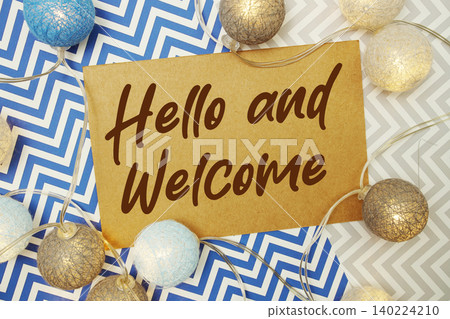 Hello and Welcome text written on paper card with LED cotton balls decorations on chevron background Hello and Welcome text written on paper card with LED cotton balls decorations on chevron background 140224210