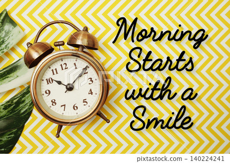 Morning Starts with a Smile text with alarm clock and monstera leave on yellow background 140224241