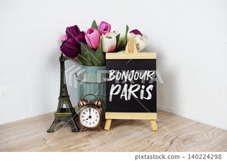 Bonjour Paris text written on easel with eiffel and alarm clock on wooden background 140224298