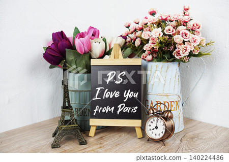 PS I love you from Paris text with eiffel tower model and alarm clock and flower in metal vase decoration on wooden desk PS I love you from Paris text with eiffel tower model and alarm clock and flower in metal vase decoration on wooden desk 140224486
