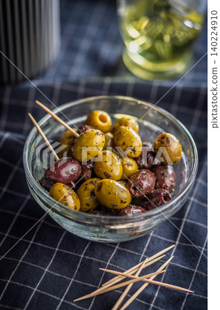 Marinated Green and Kalamata Olives in Glass Bowl With Toothpicks on Checked Cloth Marinated Green and Kalamata Olives in Glass Bowl With Toothpicks on Checked Cloth 140224910