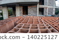 Close-up of hollow red clay bricks in the foreground of a building construction site with a concrete and briquette structure in progress. Real estate development. 140225127