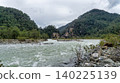 Namnam River flows through rocky banks and lush green pine forest in Mugla, Turkey. Wild mountain river landscape under a cloudy sky. 140225139