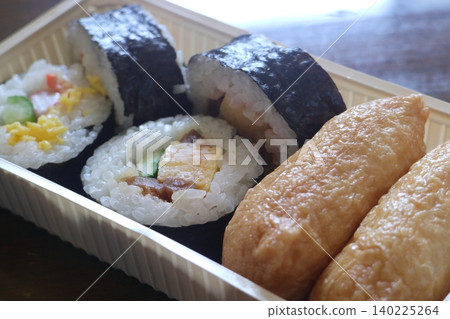 A bento box containing futomaki and inari sushi. 140225264