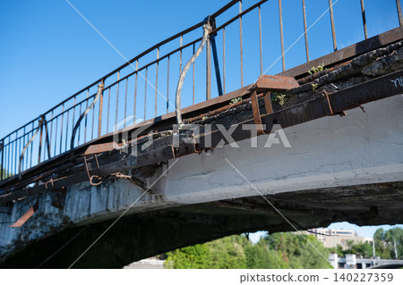 Old damaged concrete bridge in emergency condition with rusty metal railings and cracked structure Old damaged concrete bridge in emergency condition with rusty metal railings and cracked structure 140227359
