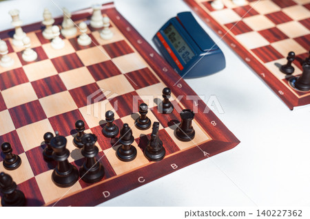 Professional chess tournament setup with wooden boards digital timer clock and pieces ready for game Professional chess tournament setup with wooden boards digital timer clock and pieces ready for game 140227362