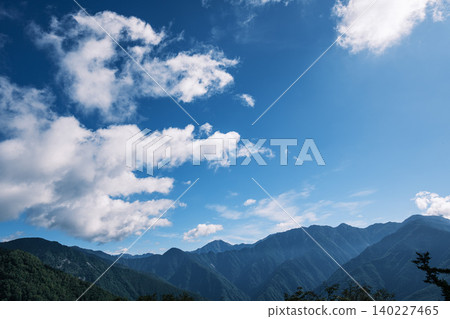 A panoramic view of white clouds drifting against the backdrop of Japan's majestic mountain ranges and a dramatic blue sky. A panoramic view of white clouds drifting against the backdrop of Japan's majestic mountain ranges and a dramatic blue sky. 140227465