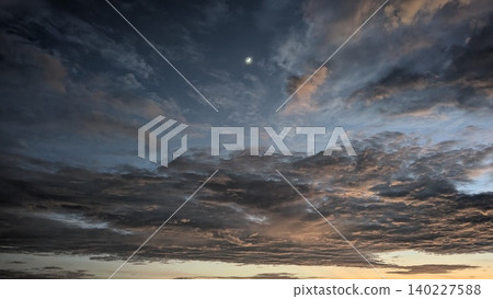 Wide scenic view captures heavy textured dark altocumulus cloud layers at dawn. A small crescent moon shines in blue morning skies, creating a beautiful dramatic natural background template. Wide scenic view captures heavy textured dark altocumulus cloud layers at dawn. A small crescent moon shines in blue morning skies, creating a beautiful dramatic natural background template. 140227588