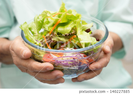 Asian elderly woman patient eating salmon stake and vegetable salad for healthy food in hospital. Asian elderly woman patient eating salmon stake and vegetable salad for healthy food in hospital. 140227885