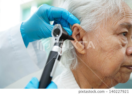 Otolaryngologist or ENT physician doctor examining senior patient ear with otoscope, hearing loss problem. Otolaryngologist or ENT physician doctor examining senior patient ear with otoscope, hearing loss problem. 140227921