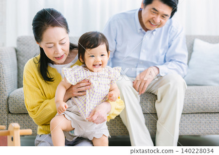 客廳裡,孩子和家人正在玩耍:嬰兒、祖母、祖父 客廳裡,孩子和家人正在玩耍:嬰兒、祖母、祖父 140228034