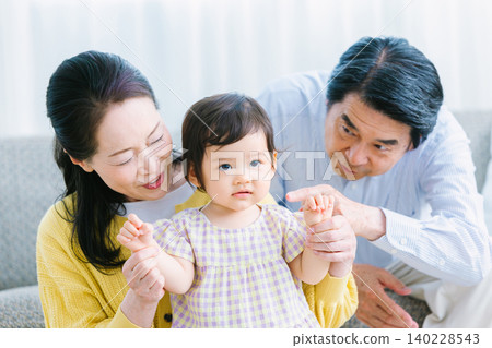 客廳裡,孩子和家人正在玩耍:嬰兒、祖母、祖父 客廳裡,孩子和家人正在玩耍:嬰兒、祖母、祖父 140228543