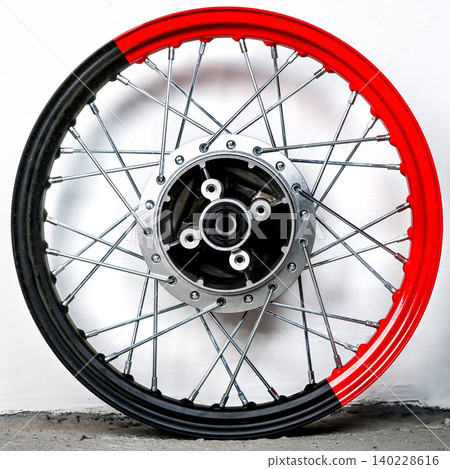 Bicolor red and black motorcycle wheel rim with silver spoke and metal hub isolated on white background for motorbike custom tuning and repair part 140228616
