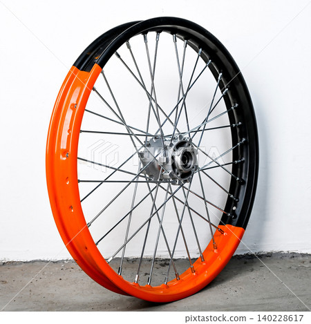 Bicolor orange and black motorcycle wheel rim in perspective view with silver spoke and hub isolated on white background for motorbike custom and repair 140228617