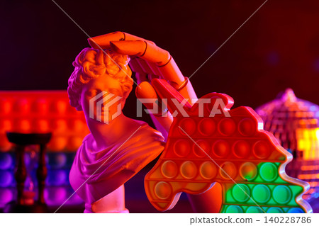 Classical sculpture bust holding colorful pop it toy with vibrant neon lighting effect Classical sculpture bust holding colorful pop it toy with vibrant neon lighting effect 140228786