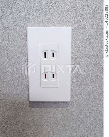 A residential power outlet installed on a white painted wall. 140228892