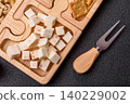 A tray with cubes of mozzarella, and Parmesan cheese, nuts, and crackers. Cheese, crackers, and nuts 140229002