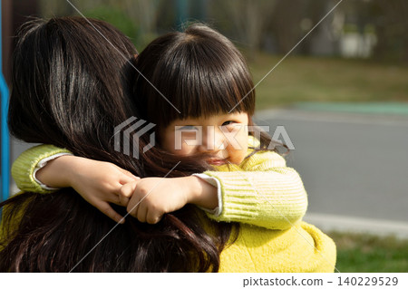 Affectionate Asian mother and daughter sitting on grass and laughing together, emotional connection and family happiness. Affectionate Asian mother and daughter sitting on grass and laughing together, emotional connection and family happiness. 140229529