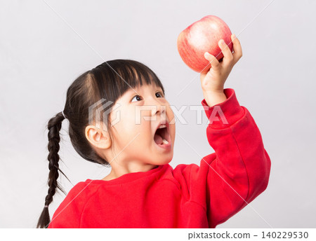 Surprised Asian girl looking at a big red apple with mouth wide open, healthy diet and snack for kids concept. Surprised Asian girl looking at a big red apple with mouth wide open, healthy diet and snack for kids concept. 140229530