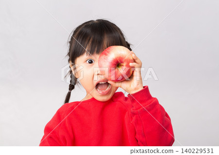 Surprised Asian girl looking at a big red apple with mouth wide open, healthy diet and snack for kids concept. Surprised Asian girl looking at a big red apple with mouth wide open, healthy diet and snack for kids concept. 140229531