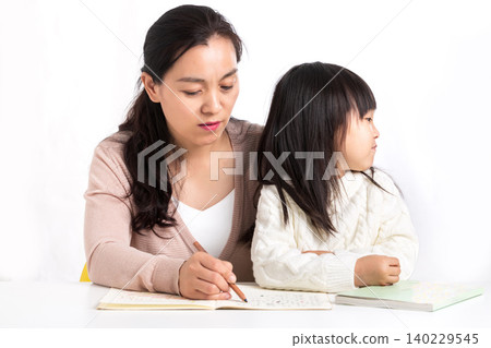 Asian Mother Helping Child with Homework Showing Concern and Guidance 140229545