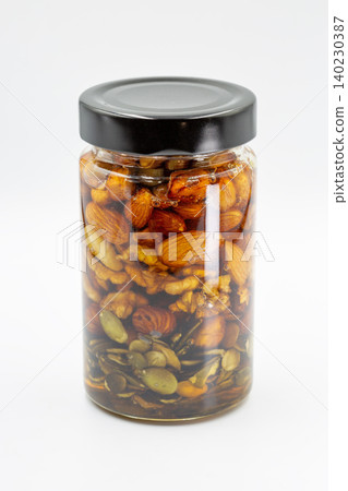 Glass jar with mixed nuts and honey closeup on white. Glass jar with mixed nuts and honey closeup on white. 140230387