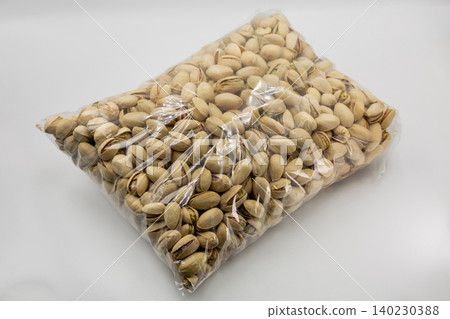 Transparent plastic bag with salted pistachios closeup on white. Transparent plastic bag with salted pistachios closeup on white. 140230388