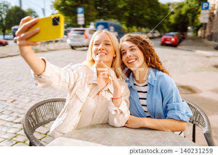 Beautiful woman friends take selfie together, while sitting at outdoor coffee shop. Tourism concept. Beautiful woman friends take selfie together, while sitting at outdoor coffee shop. Tourism concept. 140231259