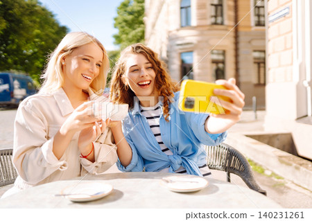 Beautiful woman friends take selfie together, while sitting at outdoor coffee shop. Tourism concept. Beautiful woman friends take selfie together, while sitting at outdoor coffee shop. Tourism concept. 140231261