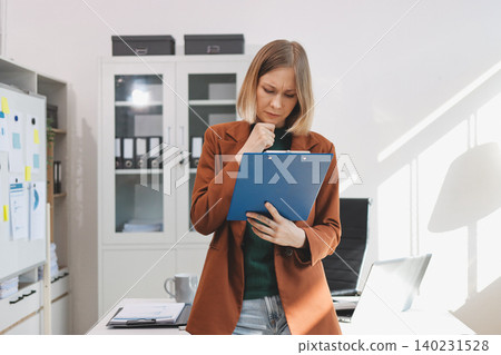 Woman smiling to herself as she works in an office Woman smiling to herself as she works in an office 140231528