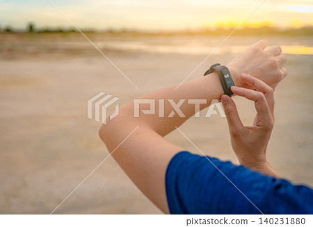 Young Asian woman touching smart band after running in the morning. Wearable computer. Heart rate monitor bracelet. Fitness device. Activity or fitness tracker. Smart watch connected device. Wristband Young Asian woman touching smart band after running in the morning. Wearable computer. Heart rate monitor bracelet. Fitness device. Activity or fitness tracker. Smart watch connected device. Wristband 140231880