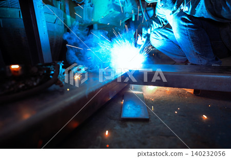 Welder welding metal with argon arc welding machine and has welding sparks. A man wears protective gloves. Safety in industrial workplace. Welder working with safety. Worker in steel industry factory. Welder welding metal with argon arc welding machine and has welding sparks. A man wears protective gloves. Safety in industrial workplace. Welder working with safety. Worker in steel industry factory. 140232056