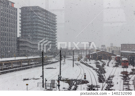 被白雪覆蓋的火車站、被白雪覆蓋的鐵軌以及周圍的城鎮景色。 被白雪覆蓋的火車站、被白雪覆蓋的鐵軌以及周圍的城鎮景色。 140232090