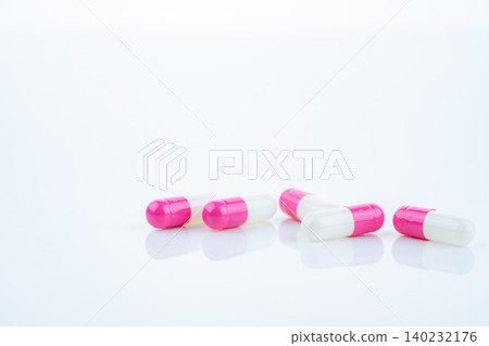 Pink-white antibiotic capsules spread on white background. Prescription drug. Antibiotic resistance in modern medicine. Healthcare and pharmaceutical industry. Medical care, pharmaceutical research. Pink-white antibiotic capsules spread on white background. Prescription drug. Antibiotic resistance in modern medicine. Healthcare and pharmaceutical industry. Medical care, pharmaceutical research. 140232176