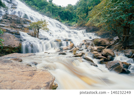 Beautiful waterfall with a lush green forest in the background. The water is flowing down the rocks and creating a beautiful scene. Sustainable waterfall in lush forest promoting water sustainability. 140232249
