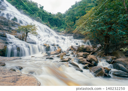 Beautiful waterfall with a lush green forest in the background. The water is flowing down the rocks and creating a beautiful scene. Sustainable waterfall in lush forest promoting water sustainability. 140232250
